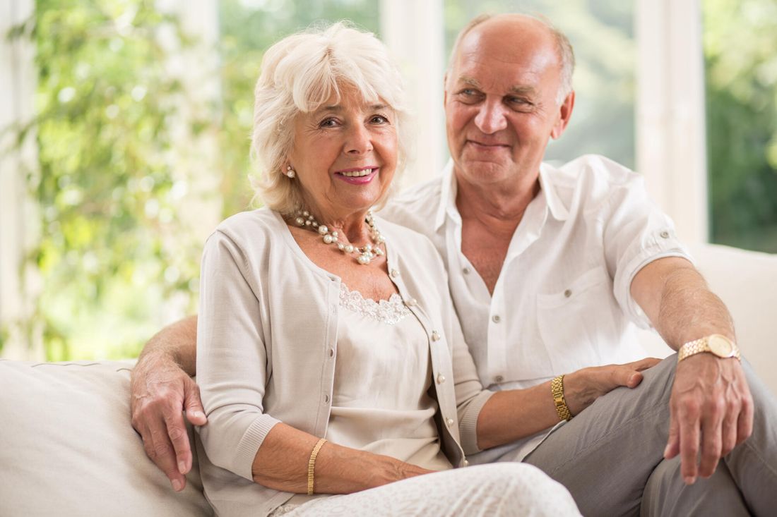 Smiling retired couple relaxing on a sofa in a bright room